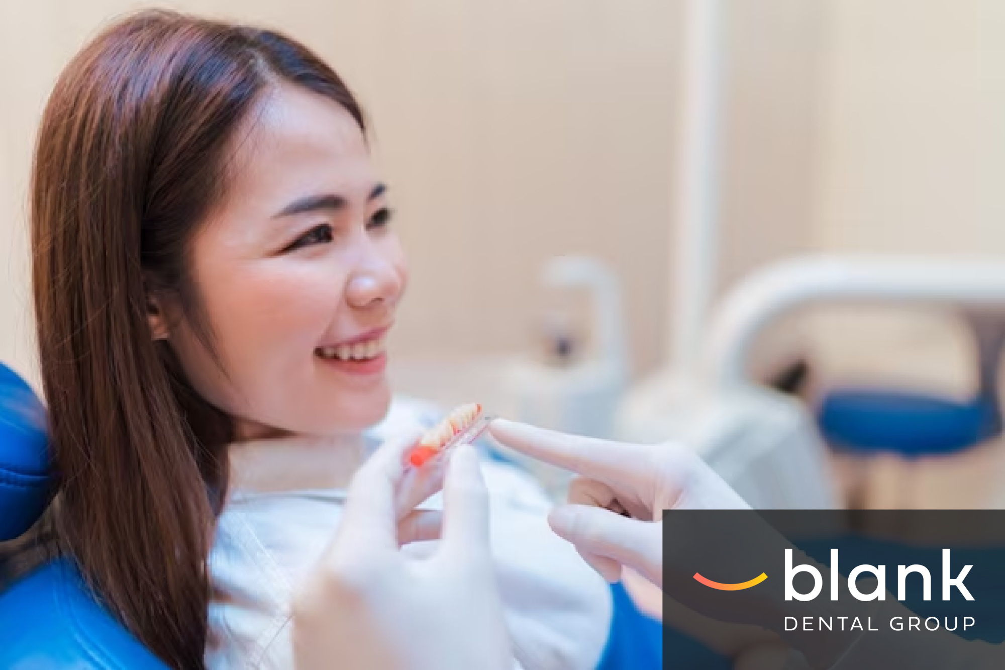 A woman is smiling while a dental professional shows her a dental model at Blank Dental Group.